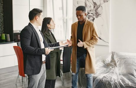 Three professionals engage in a conversation inside a contemporary office, promoting teamwork.