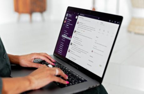 A woman types on a laptop using a messaging app in a modern office setting.